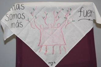 Bandana with artwork of three human figures with arms raised. The arms are stylized as tree branches with leaves on them.