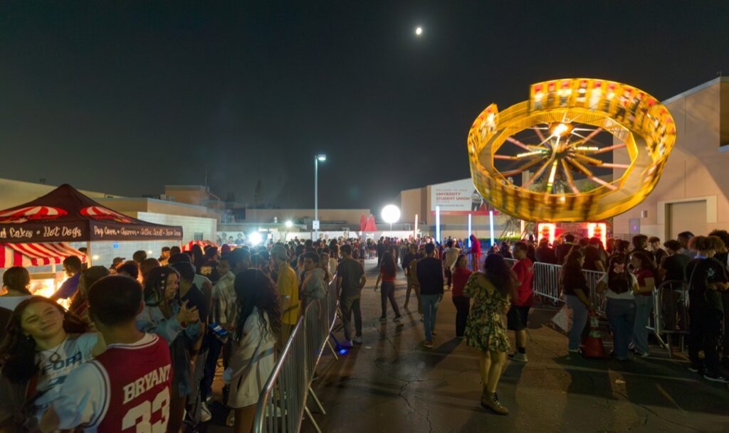 The line for food and Roundup ride in the foreground as the ride spins in the air in the background.