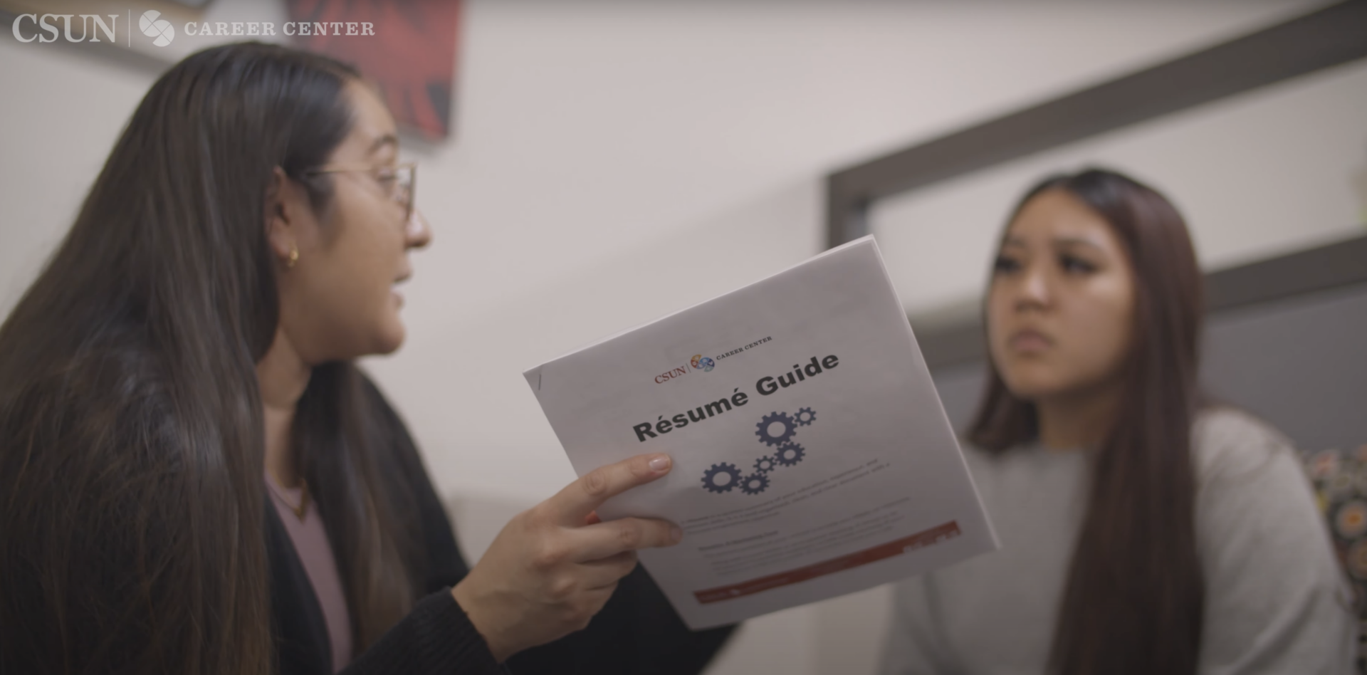 Career center staff holds resume guide brochure while speaking with student in her office.