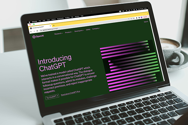 A laptop displaying a webpage about ChatGPT, with the text “Introducing ChatGPT” and an abstract design.