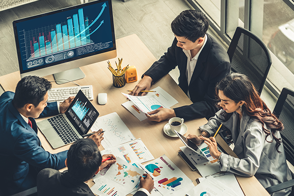 Four professionals discussing charts and graphs around a conference table in a modern office.