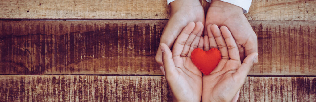 one person handing a decorative heart to another