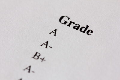 Close-up of a list of grades on a white paper, including A, A-, and B+.