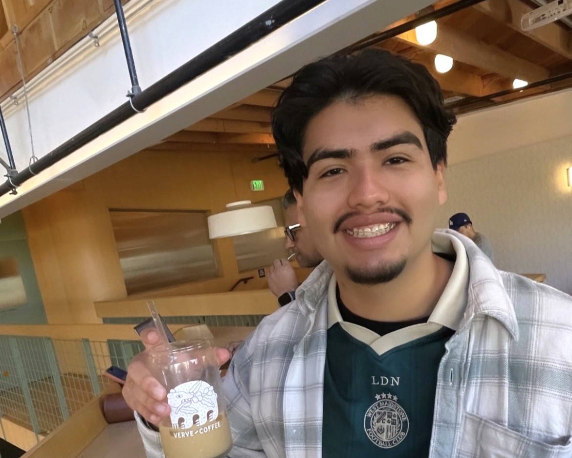 Alex smiling and holding a cup of coffee