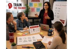 A diverse group of four individuals participates in a training session, while a woman stands at a whiteboard presenting information. Materials are spread out on the table, including sticky notes and notebooks.