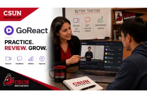 A woman guides a young man on using the GoReact software, displayed on a laptop in front of them, with a whiteboard in the background also visible.
