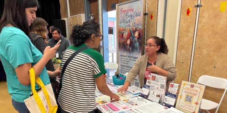 FFRC staff member at table talking to Resource Fair attendees.